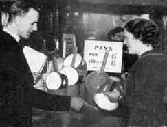 a period photograph of a salesman suggesting cookware to a customer