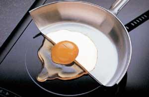 an egg with half on metal frying and half on the bare cooktop raw